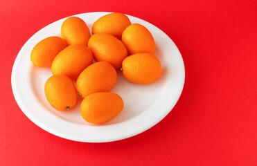 Fresh ripe kumquats fruit on a red background