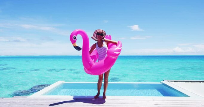 Vacation travel fun. Funny woman dancing happy and cheerful and funny with flamingo swimming pool float around waist excited of tropical hotel holiday getaway