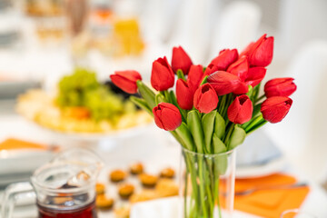 Obraz na płótnie Canvas vase with a bouquet of red tulips on the festive table. serving the table with appetizers, canapes, salads in jars. Catering. restaurant business.