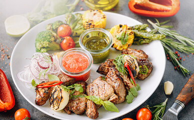 shish kebab and vegetables grilled and served on a white plate