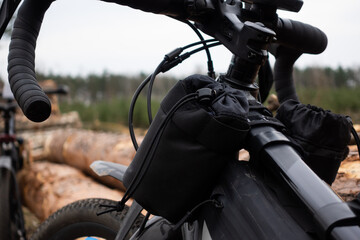 Adventure on a gravel bike in the woods. View of the bicycle handlebar with accessories. Taken under cloudy skies