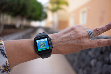 Coronavirus. Arm of woman wearing electronic watch showing digital passport of coronavirus vaccination done. Mobile app for immunized people