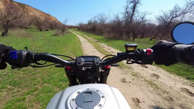 A motorcyclist rides along a trail with a beautiful landscape. View from behind the wheel of a motorcycle. First-person view. POV. The view of a biker riding through a picturesque nature. Slow-motion
