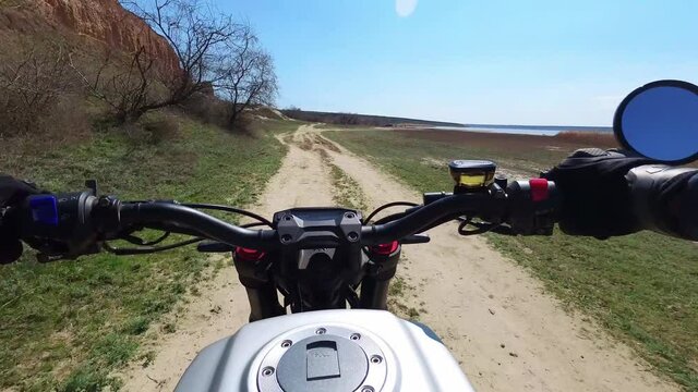 A motorcyclist rides along a trail with a beautiful landscape. View from behind the wheel of a motorcycle. First-person view. POV. The view of a biker riding through scenic nature. 