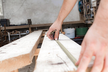 Male carpenter working with wood material in a garage.