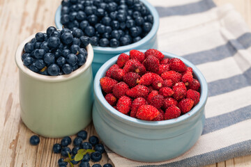 Organic bilberry and strawberry on wooden table