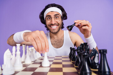Photo of young happy cheerful smiling funky geek nerd man in glasses playing chess isolated on...