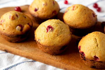 Homemade Cranberry Muffins with Orange Zest on a rustic wooden board on cloth, low angle view. Close-up.