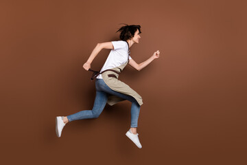 Fototapeta na wymiar Full length body size profile side view of attractive cheerful girl jumping running fast service isolated over brown color background