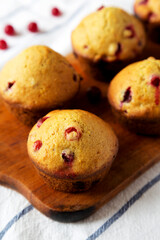Homemade Cranberry Muffins with Orange Zest on a rustic wooden board on cloth, low angle view. Close-up.