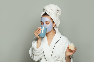 Attractive spa woman in cosmetic face mask eating breakfast and drinking coffee. Female morning day routine