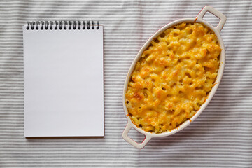 Homemade Macaroni and Cheese Pasta with blank notepad, top view. Flat lay, overhead, from above.