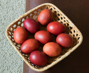 Brown dyed Easter eggs in a square wicker basket. On a white-brown background. View from above. Registration for the holiday.
