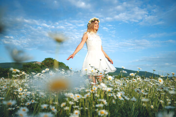 Pretty girl with a hat in her hand walks in a field with flowers and smiles sincerely. High quality photo.
