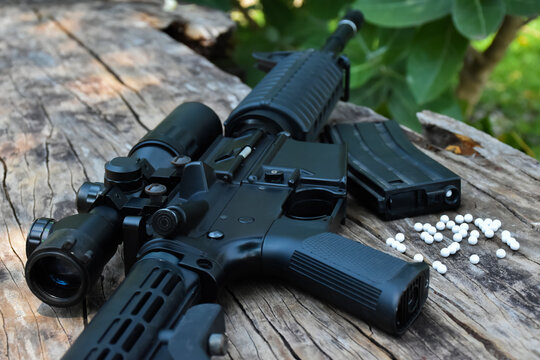Close up view of black long barreled automatic rifle or bb gun on wooden floors