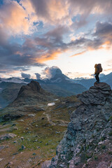 A hiker walking on a mountain meadow in spring or autumn. Hiking in the Dolomite mountains. Hiker, Backpacking on top of a mountain cliff landscape and trekking in it. Concept: Adventure, Art, Travel
