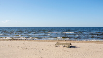 Beach bench on the deserted beach on a bright sunny day of the beginning of spring