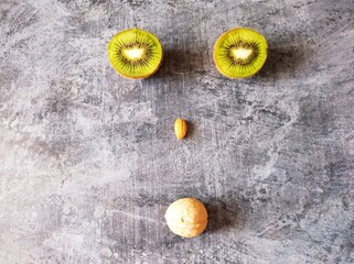 A face made of fruits and nuts. The benefits of fruits and nuts. Kiwis, walnuts, almonds.