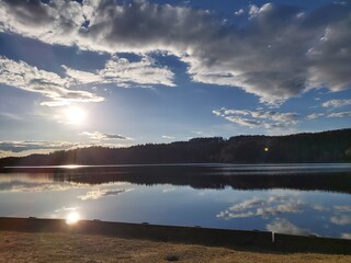 clouds mirroring in flat sea with sun