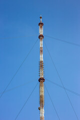 Obraz premium High telecommunications tower with antennas against the blue sky.