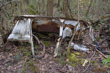 Illegal dumping: remains of an old abandoned car (oldtimer) in the forest