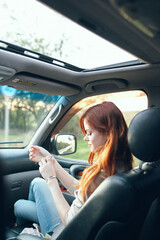 Fototapeta premium woman with an open window in the front seat of a car gesturing with her hands interior salon fellow traveler