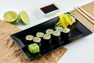 Classic Japanese sushi roll - hosomaki with avocado, served in a black plate. White background. Rolls maki