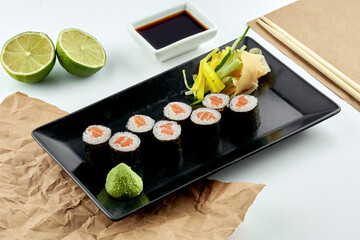 Classic Japanese sushi roll - hosomaki with salmon, served in a black plate. White background. Rolls maki