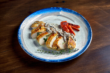Appetizing baked chicken fillet with cheese and mushroom sauce, served on a white plate. Wood background