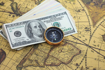 Classic navigation compass on background of old world map and american dollars as symbol of tourism with compass, travel with compass and outdoor activities with compass
