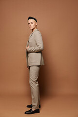 A young woman wearing official-style clothes isolated on a beige background. Model blond girl in modish suit isolated at the background with copy space