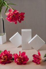 Gift or present box wrapped in white paper and tulip flowers on pink table. Copy space