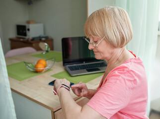 Senior woman checking health information with smart watch. Pulse, temperature, blood pressure, steps and sleep. Elderly people and technology concept, modern healthcare and support