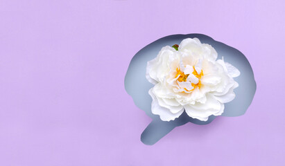 Top view of purple paper and brain shape of it, white flower as a symbol of peacefull and beautiful mind.Empty space