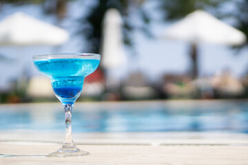 Cold blue cocktail near pool on tropical resort  copy space .