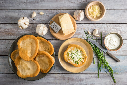 Traditional Hungarian Langos with garlic, cheese and sour cream, garnished with chopped chives shot top view
