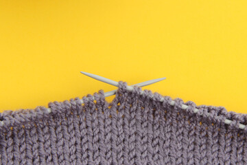 Knitted fabric made of gray woolen threads on a yellow background.Everything for needlework.The colors of 2021 are gray and yellow.Top view. Flatley.Close-up.Copyspace.