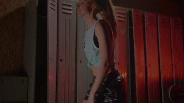 Girl get ready for boxing training in the locker room. Red Neon light