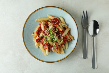 Plate with pasta with tomato sauce and ingredients on white textured background