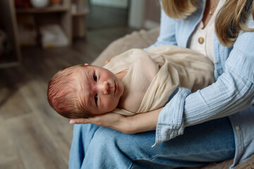 Obraz na płótnie Canvas Little newborn baby boy in mom's arms at home 