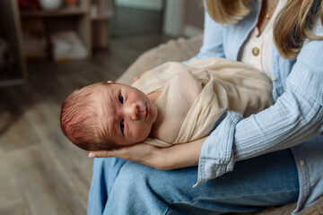 Fototapeta premium Little newborn baby boy in mom's arms at home 