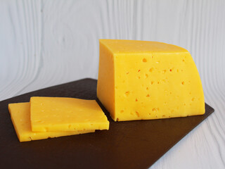 Piece of delicious cheese on a board isolated on white. close-up.	
