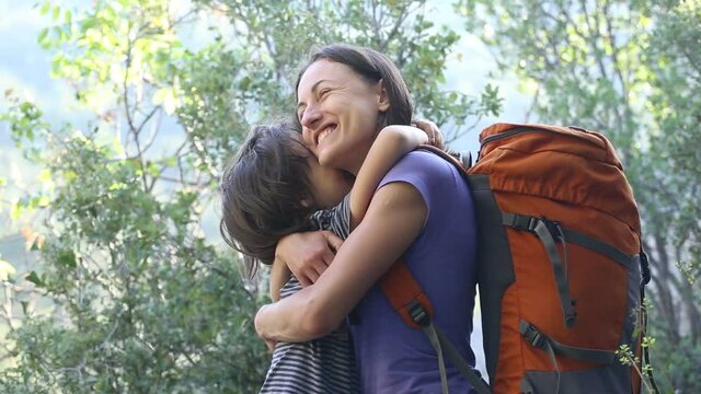 A child hugs mom for a walk in the forest. The boy congratulates mom on his mother's day. A woman with a backpack goes camping with her son. Portrait of a mother with her son.