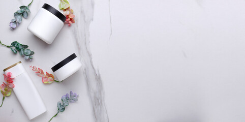 Top view of collection of white bottles of beauty products and eucalyptus leaves on the white table.Banner for beauty ad