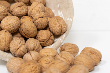 ripe walnuts spilling out of a wicker basket on a white background close-up, selective focus