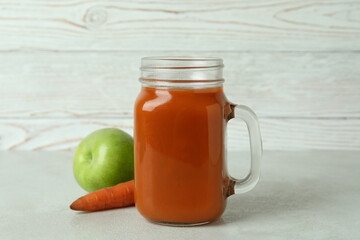 Glass jar of juice and ingredients against white wooden background