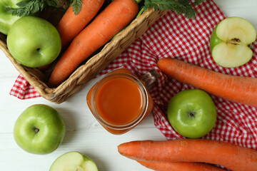 Jar of apple - carrot juice and ingredients on white wooden background