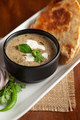 Close-up of Methi, matar malai with white curry. Served with paratha or roti. A popular, delicious Indian recipe in black bowl.
