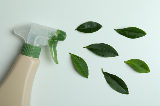 Blank detergent spray bottle and leaves on white background