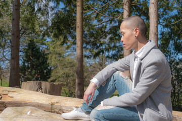 切り株に座る坊主の細身の男性